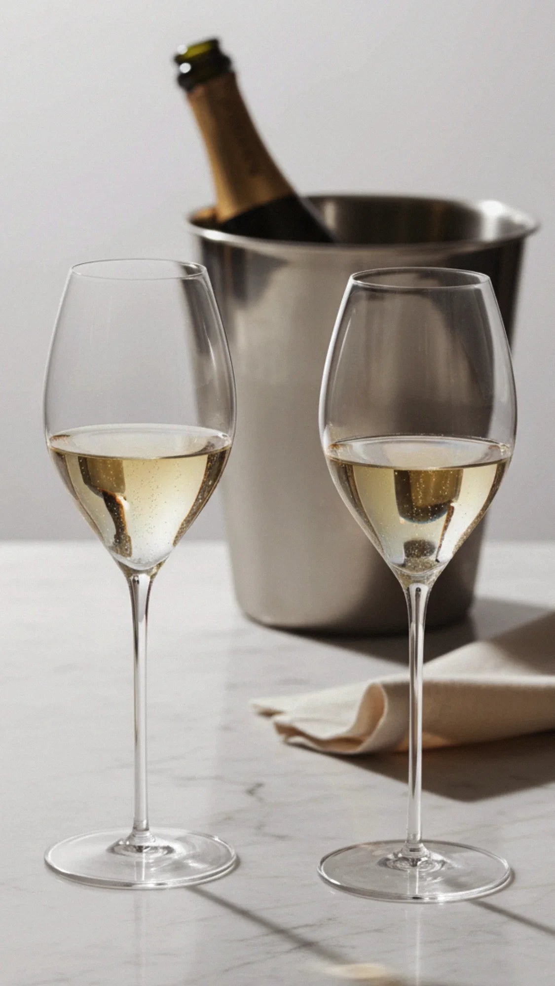 Champagneglas på vitt marmorbord med en champagneflaska